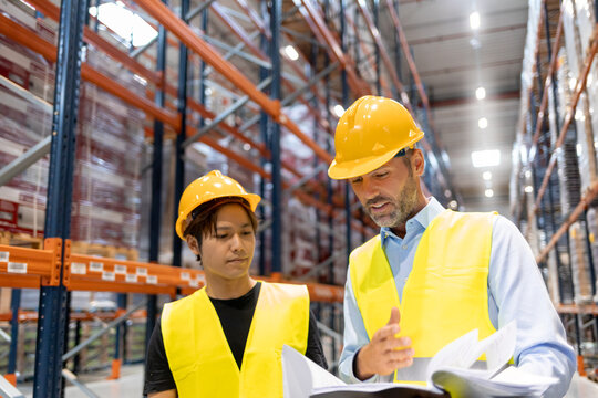 Warehouseman and manager talking about plans of inventory in large warehouse