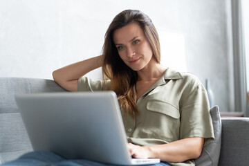 Fototapeta premium Woman using a laptop in her living room. Working from home in quarantine lockdown. Social distancing.