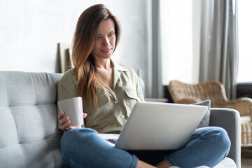 Woman using a laptop in her living room. Working from home in quarantine lockdown. Social...