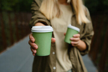 Green paper cup with coffee in woman hand. Time for drink coffee in city. Coffee to go. Enjoy...