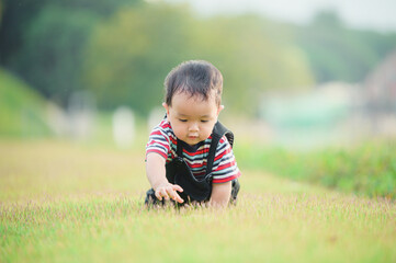 Cute laughing baby boy having fun sitting on green grass