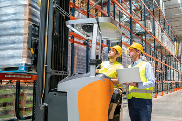 Worker using forklift and talking with his manager in large warehouse