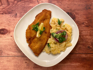 Golden breaded fish plaice fillet with potato salad and lemon. 