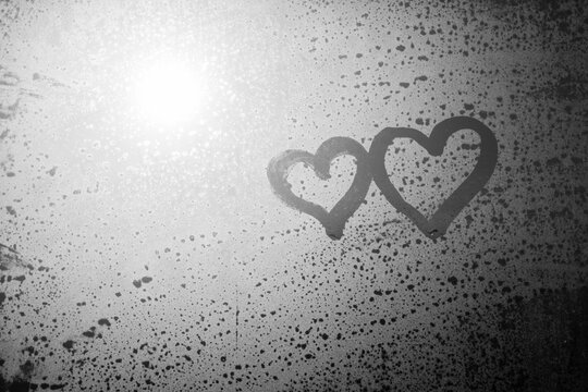 Close up hand drawing of a heart on a natural foggy window glass background. Valentine's day inspiration, close-up photo. An emotional sense of hope and love.
