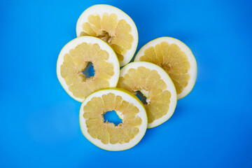 Top view of round pomelo slices on light blue background.