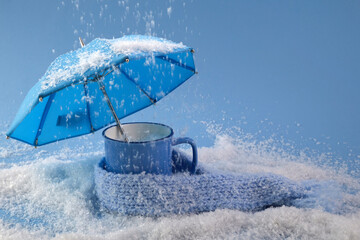 Blue umbrella and cup of coffee on blue background with snow. Blue monday concept.