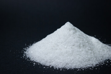 Heap of salt on a black background. Excessive salt intake. Coarse salt