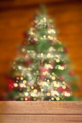 Empty wooden table top and blurred bokeh Christmas tree on the background.