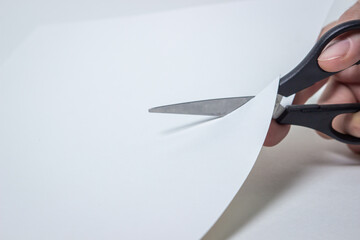 Scissors cut through the white paper. Working with paper.