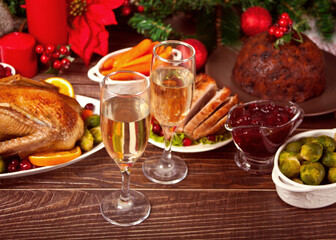 Table served for thanksgiving or Christmas dinner. Two glasses of wine or champagne. Stuffed roasted turkey, pudding and ham. Traditional celebrating holiday. Top view.