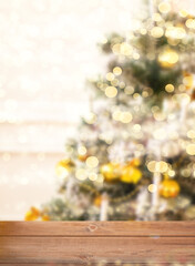 Empty wooden table top and blurred bokeh Christmas tree on the background.