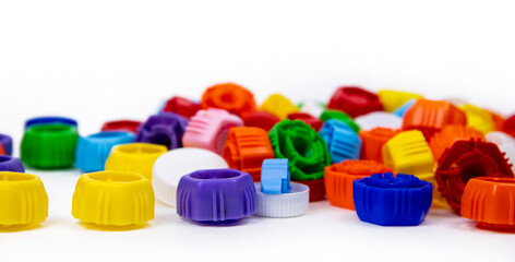 Multi-colored plastic bottle caps on a white background. Ecology and recycling concept.