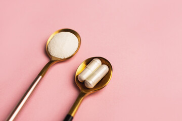 Collagen powder and pills on pink background. Extra protein intake. Natural beauty and health supplement for skin, bones, joints and gut. Plant or fish based. Flatlay, top view. Copy space.