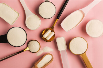 Collagen powder and pills spoons on pink background. Extra protein intake. Natural beauty and...