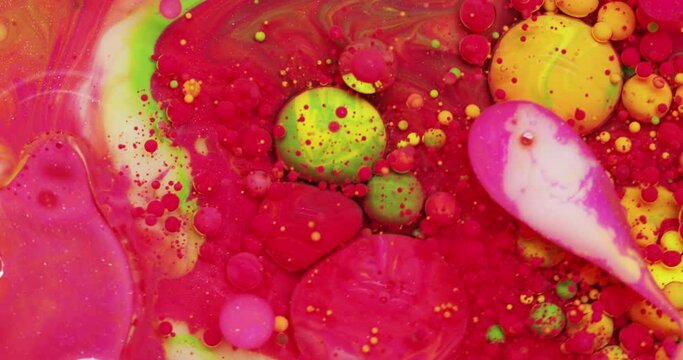 Multicolored acrylic paint bubbles move and explode in the water
