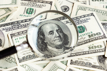 Magnifier and dollar banknotes background. 100 USA dollar bills through lens. Financial analysis. Investments. Cash and savings. American money.  Business, finance concept. Copy space.