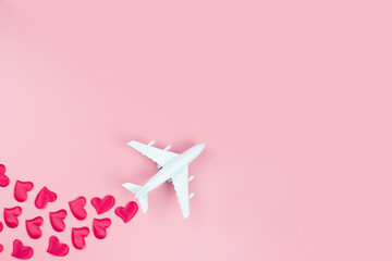 Happy Valentine's Day. Toy plane and red hearts, on a pink background