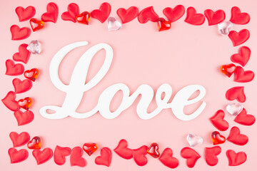 The word Love and red hearts, on a pink background. Valentine's day concept
