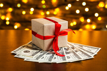 Gift box on the pile of USA 100 dollar bills on blurred lights background. American dollar....