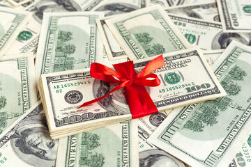 USA 100 dollar bills with red ribbon. American dollar. Christmas, New Year, Birthday, St Valentine's Day money present. Gift cost. Hundred. Finance and business concept. Christmas shopping