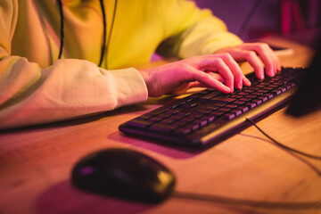 Cropped view of gamer using computer keyboard near mouse on blurred foreground © LIGHTFIELD STUDIOS