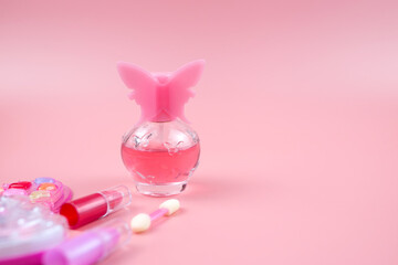 Cosmetics for little girls, baby perfume, lipstick, eye shadow, lip gloss, on a pink background.