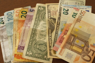 Money notes in Brazilian reais, euros and dollars on a table.