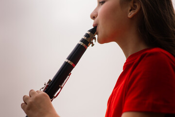 Young attractive girl playing clarinet, ebony in fall park