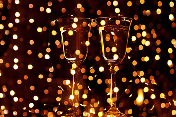Two glasses with sparkling wine champagne on a black background and glittering golden bokeh....