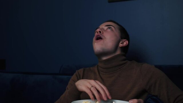 Portrait Joyful Caucasian Man Sitting On Sofa At Home Throwing Popcorn And Catching It With His Mouth, Self Isolation Time At Home Concept