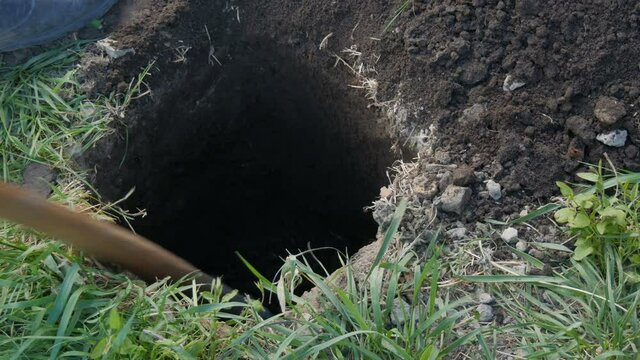 A large vintage old spade digs a hole in the ground.