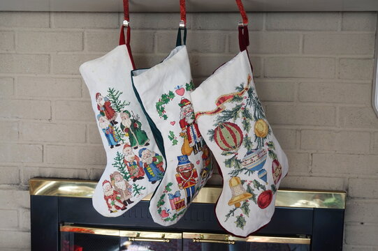Three Counted Cross Stich Christmas Stocking Hanging on Fireplace