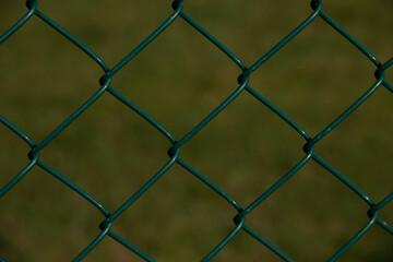 view through green chain link fence onto a green area in the background