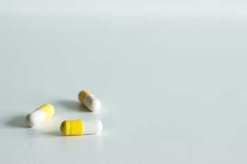 close up of three white and yellow pills on white background; isolated; cold and flu medicine 