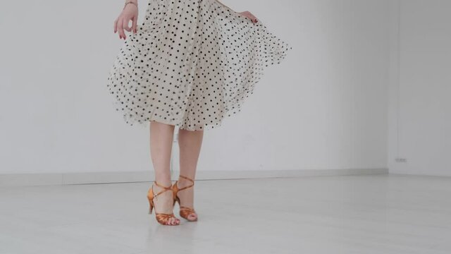 Young beautiful girl dancing ballroom dancing. A professional ballroom dancer is engaged in a large white hall.
