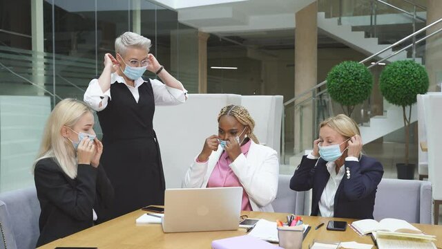 Business team having biz negotiations in office, wearing masks during coronavirus pandemic. Discussing new start-up.