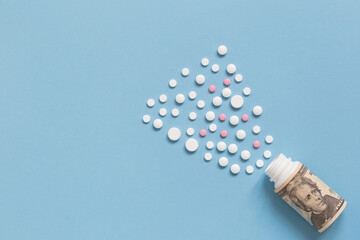 Medical bootle with dollars and variegated pills. Isolated on a blue background. The concept of insurance medicine.