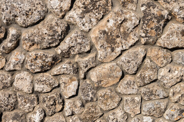 The outer facade of the building is made of natural stone of various shapes. Background texture for outdoor decoration under the Middle Ages
