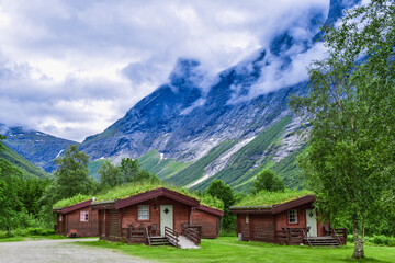 Fototapeta na wymiar Authentic cabins with green grass on the roof at the foot of the popular Troll Stair or Trollstigen serpentine road.