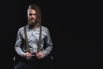 Portrait of a bearded man with an intense look standing in a dark room against a black background