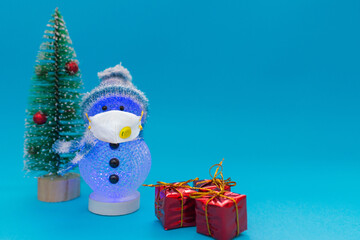 Glows in the dark snowman,wearing face mask, presents and Christmas tree with copy space.new year celebration.