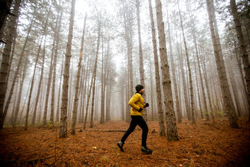 Young man running in autumn forest and exercising for trail run marathon endurance race