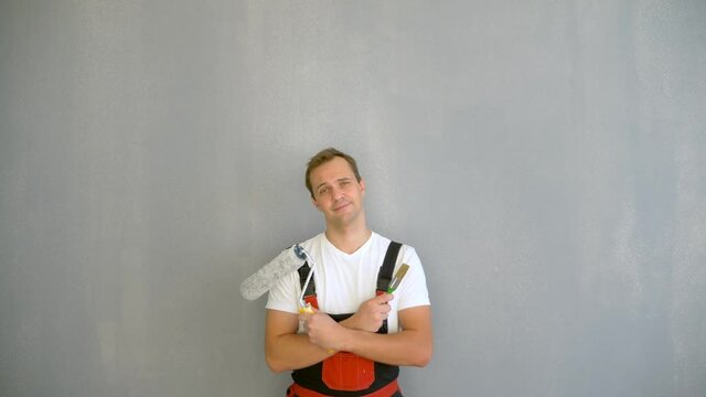 Copy space. portrait of a handsome man with a roller to paint the walls on a gray background.