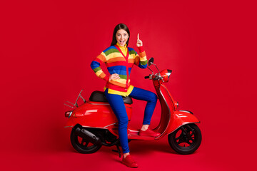 Fototapeta na wymiar Photo portrait of smart girl having idea raising finger up sitting on scooter isolated on vivid red colored background