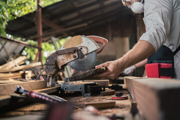 Carpenter man cutting wood with saw. craftsman working workshop factory industry.  Capenter worker with mask protection.
