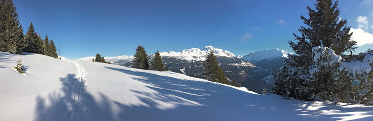 Fototapeta na wymiar footprint in the fresh snow crossing snowcapped mountain under blue sky