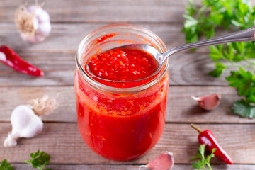 Tomato juice in a spoon in a glass jar on a wooden background