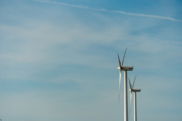 view of a modern windmill against a blue sky. The white blades of the wind turbine close up. Renewable energy source. Production of cheap and safe electricity.