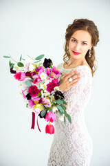 joyful girl bride in a white knitted dress posing with a bouquet of flowers
