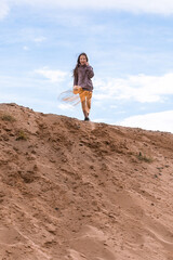 Preteen girl standing on sand hill and enjoying the space